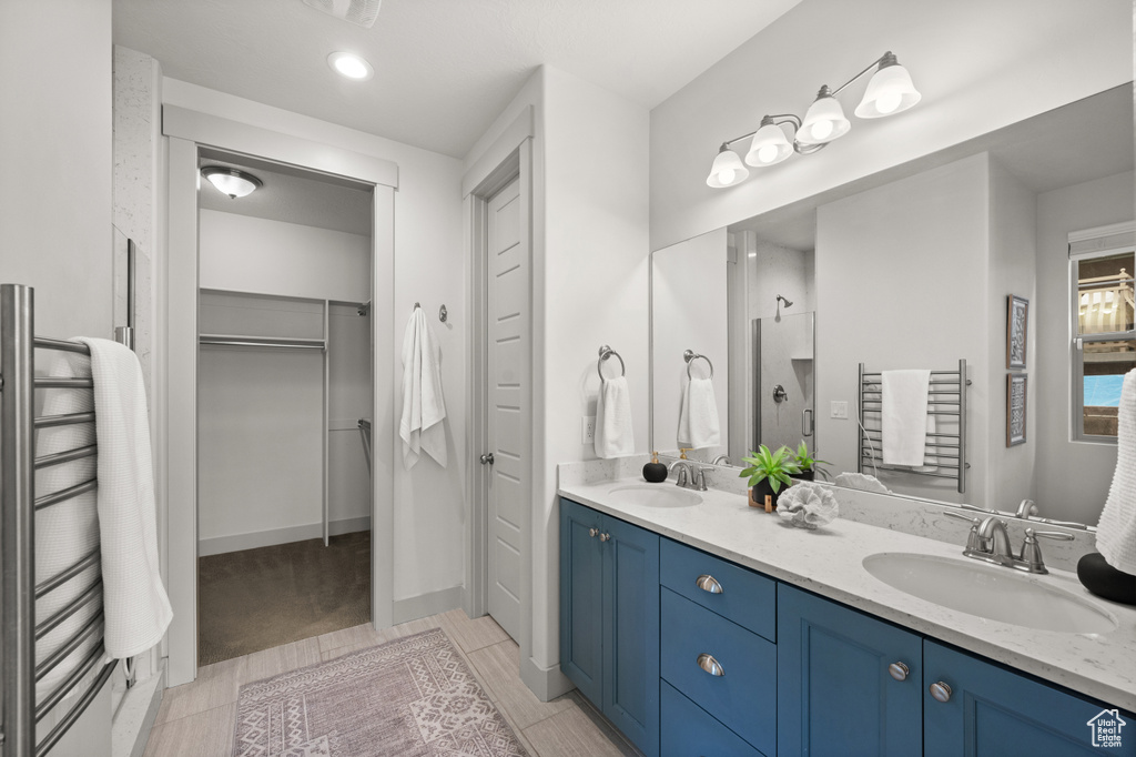 Full bathroom with double vanity, a sink, and a walk in closet