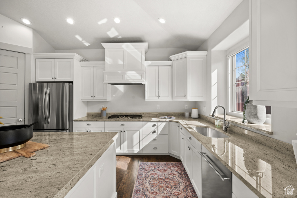 Kitchen featuring light stone counters, dark wood-style floors, white cabinets, appliances with stainless steel finishes, and a sink