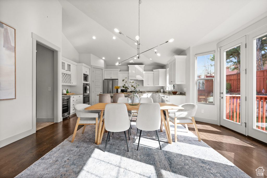 Dining space featuring baseboards, recessed lighting, dark wood-type flooring, wine cooler, and high vaulted ceiling