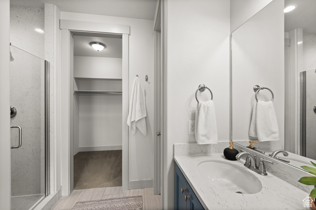 Bathroom with a shower stall, a walk in closet, and vanity