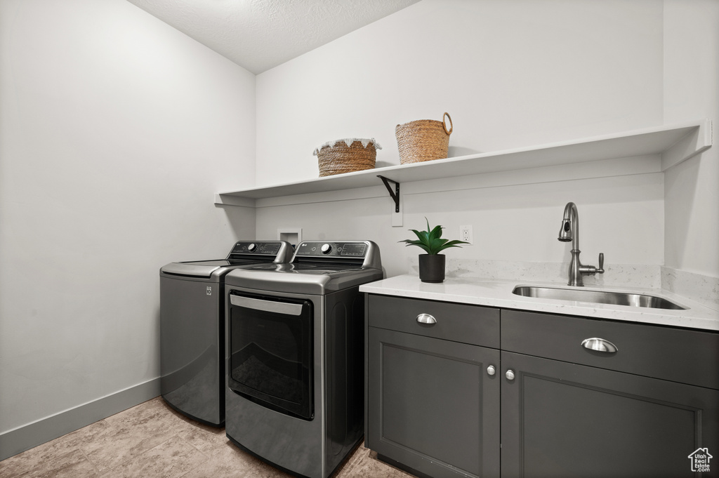 Laundry area with baseboards, separate washer and dryer, a sink, a textured ceiling, and cabinet space