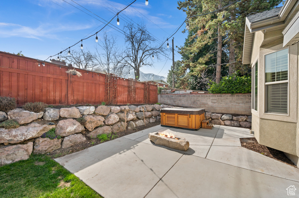 View of patio / terrace featuring a fenced backyard, a fire pit, and a hot tub