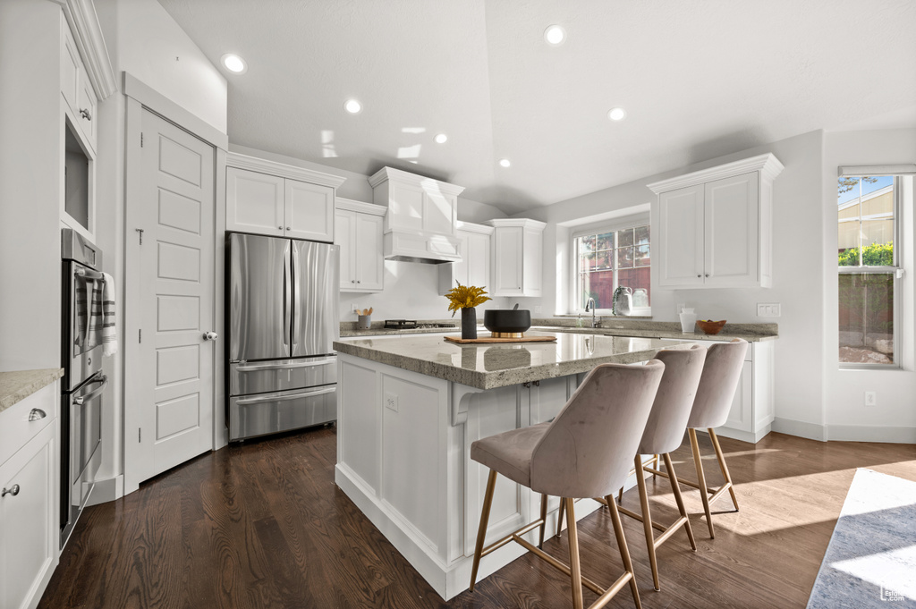 Kitchen featuring a healthy amount of sunlight, premium range hood, a kitchen island, and stainless steel appliances