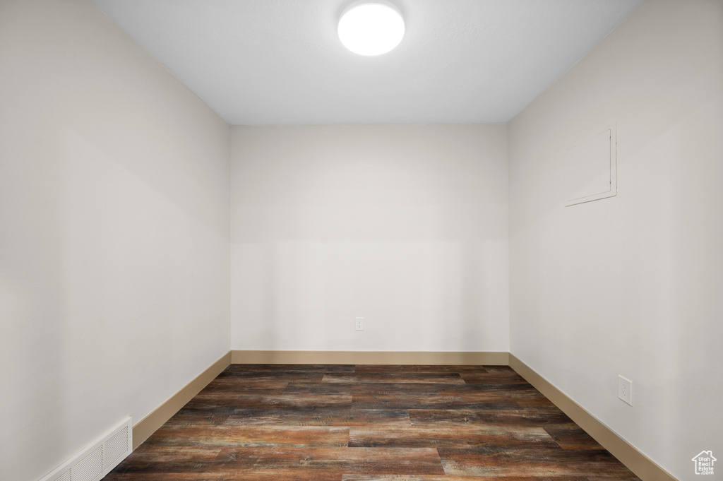 Empty room with dark wood-type flooring and visible vents