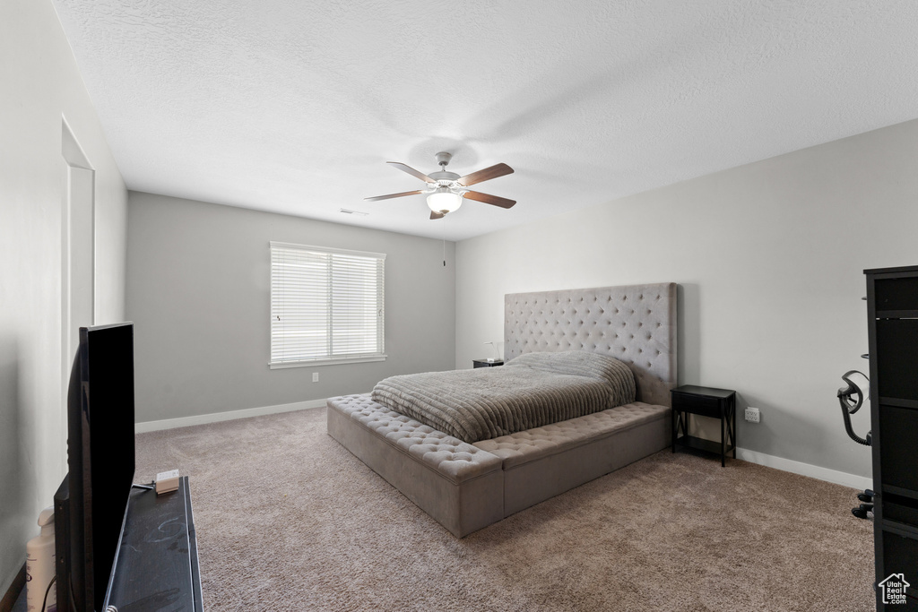 Carpeted bedroom with baseboards, a textured ceiling, and a ceiling fan
