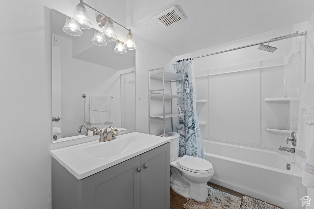 Full bathroom featuring vanity, shower / tub combo with curtain, toilet, visible vents, and wood finished floors