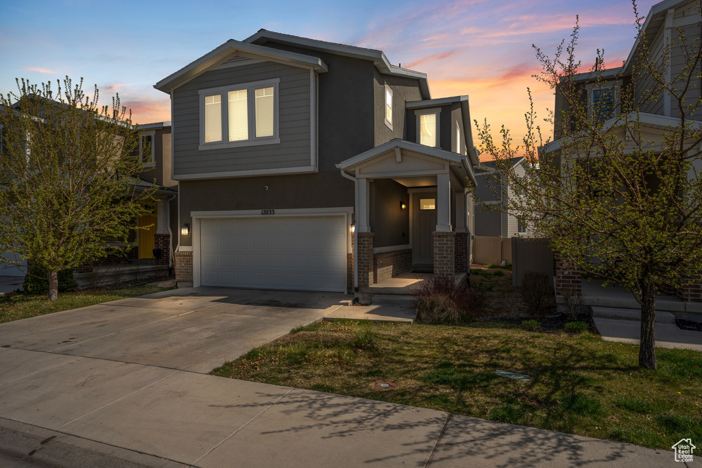 View of front facade with concrete driveway, brick siding, stucco siding, and an attached garage