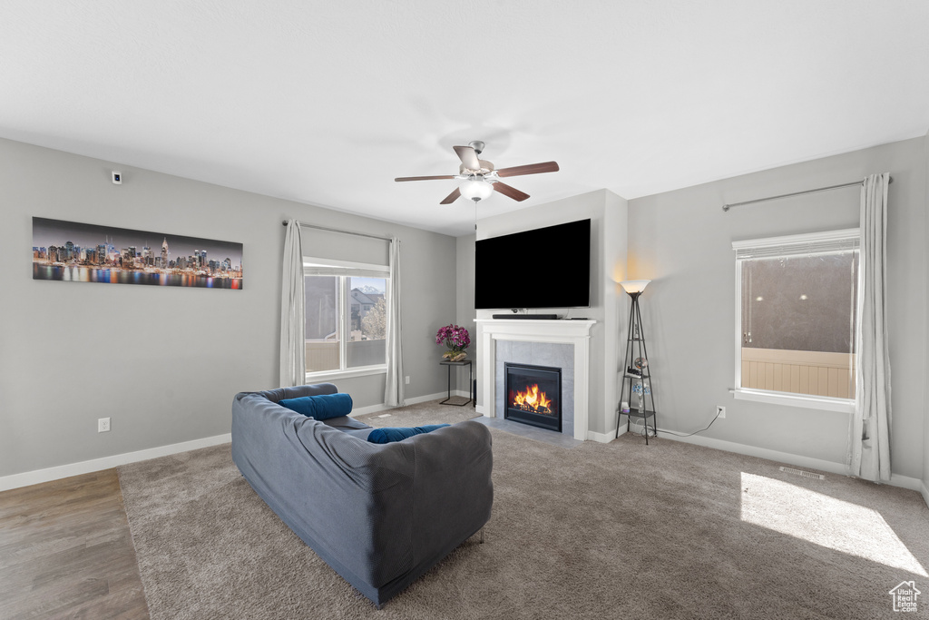Living area with a tiled fireplace, baseboards, and ceiling fan