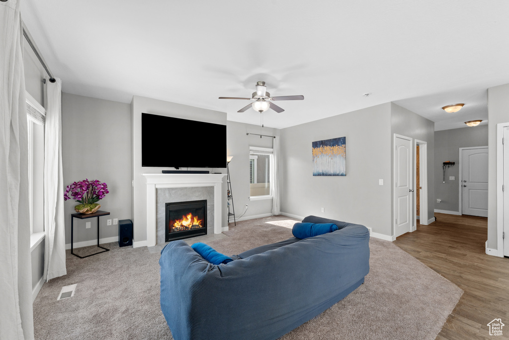 Living room featuring visible vents, ceiling fan, baseboards, and a lit fireplace
