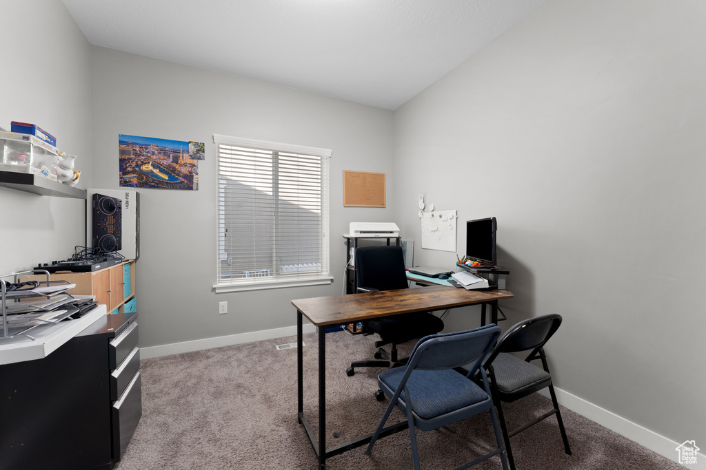 Home office with light colored carpet, baseboards, and vaulted ceiling