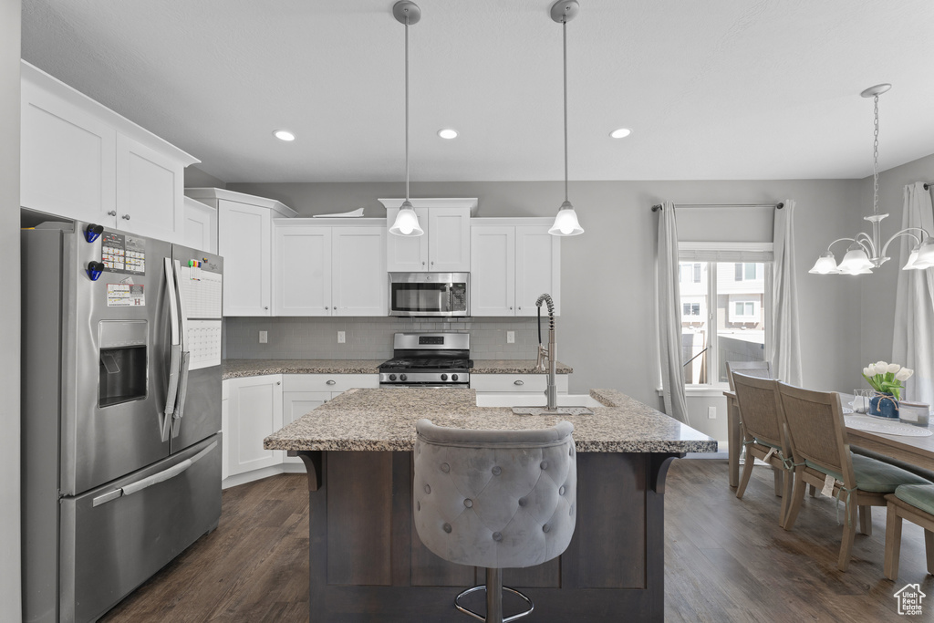 Kitchen featuring white cabinets, tasteful backsplash, dark wood-style flooring, and appliances with stainless steel finishes