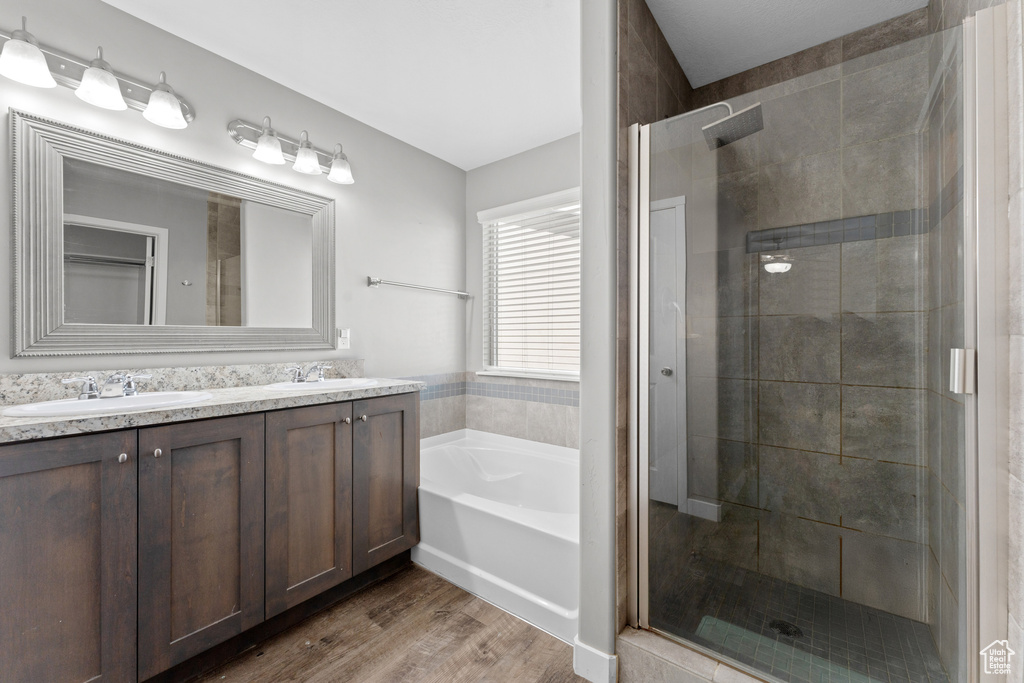 Bathroom with a shower stall, a sink, a garden tub, and wood finished floors