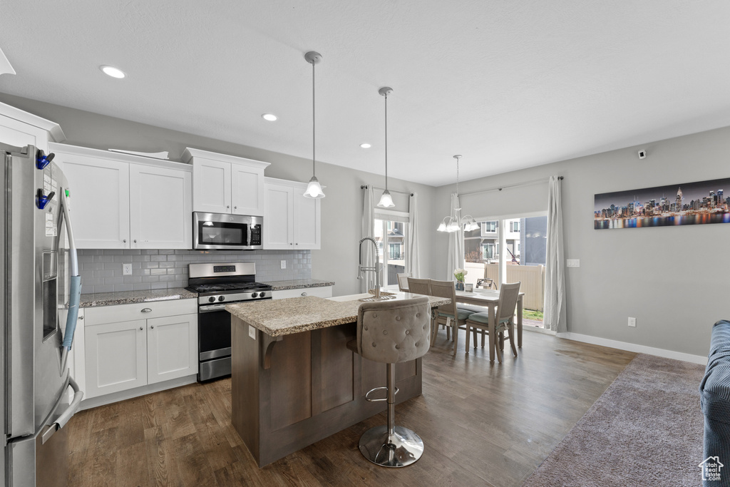Kitchen with tasteful backsplash, a sink, appliances with stainless steel finishes, dark wood finished floors, and a kitchen island