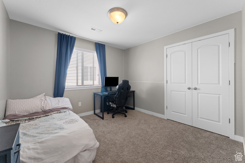 Carpeted bedroom with a closet, visible vents, and baseboards