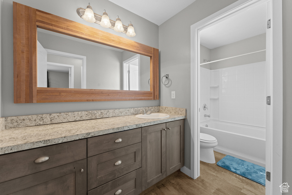 Bathroom featuring toilet, vanity, wood finished floors, and shower / bathtub combination