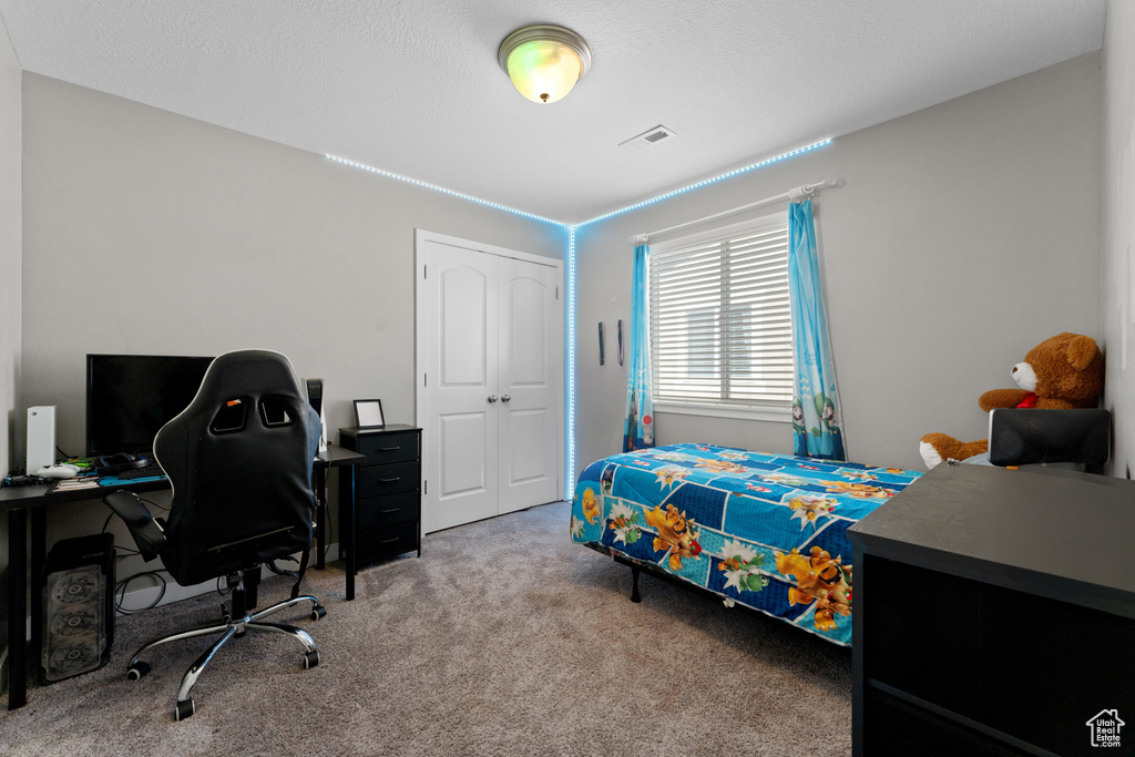 Carpeted bedroom featuring visible vents and a closet
