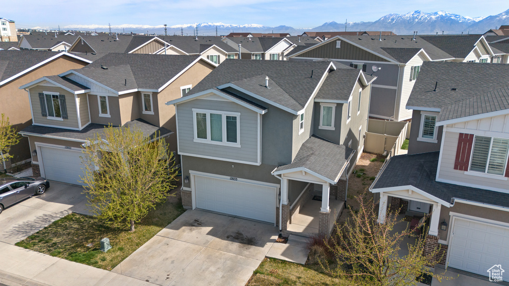 View of front of property featuring a mountain view, driveway, a residential view, and a garage