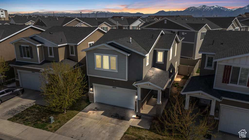 View of front of home featuring a mountain view, concrete driveway, a garage, and a residential view