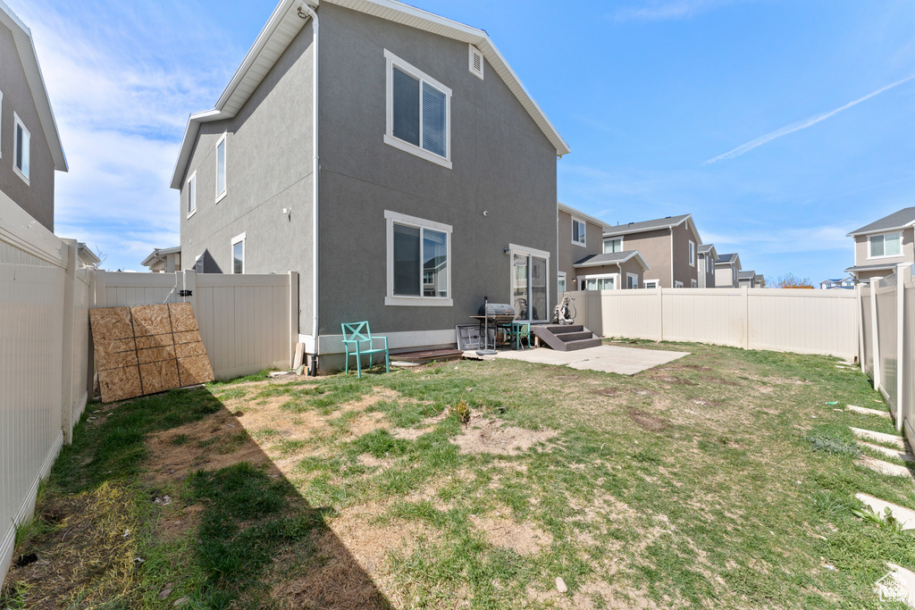 Back of house with a fenced backyard and a lawn