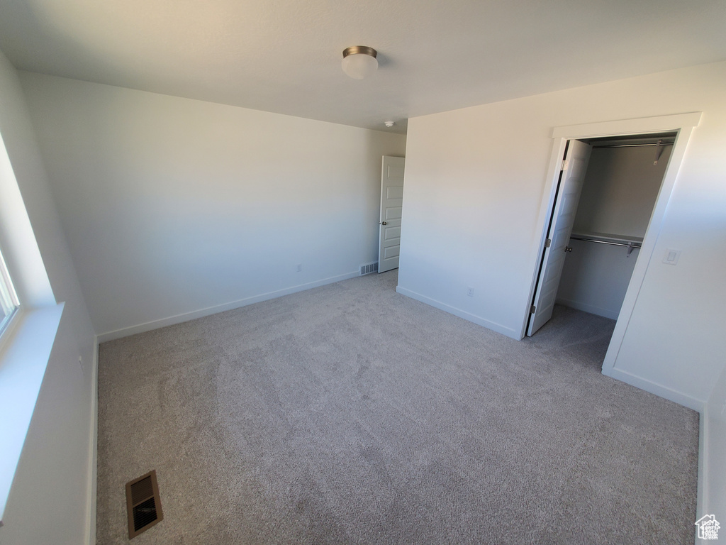 Unfurnished bedroom featuring visible vents, light colored carpet, and baseboards