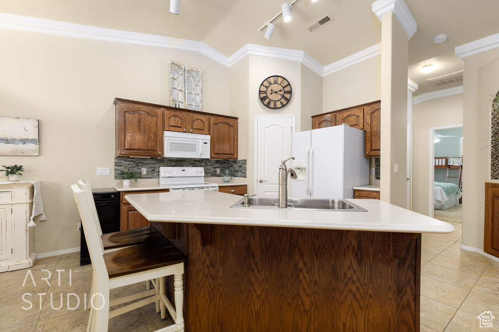 Kitchen with ornamental molding, white appliances, visible vents, decorative backsplash, and a sink