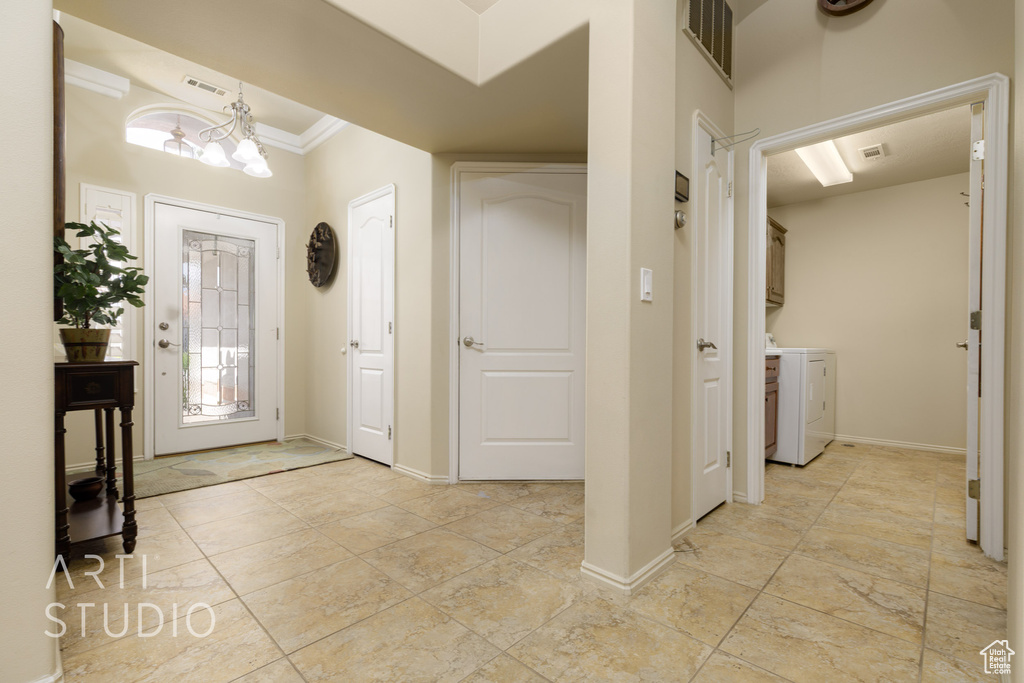 Entryway featuring a chandelier, washing machine and clothes dryer, ornamental molding, and visible vents