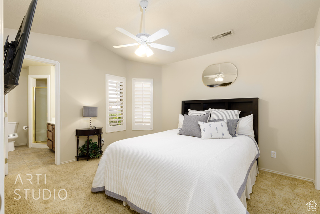 Bedroom featuring ceiling fan, connected bathroom, visible vents, light carpet, and lofted ceiling