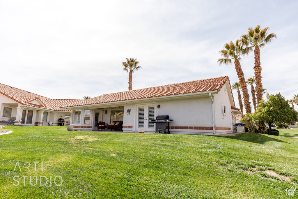 Back of property featuring a tiled roof, a patio area, a yard, and stucco siding