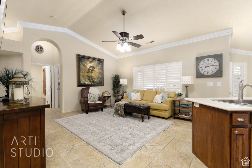 Living room featuring arched walkways, a ceiling fan, ornamental molding, vaulted ceiling, and visible vents