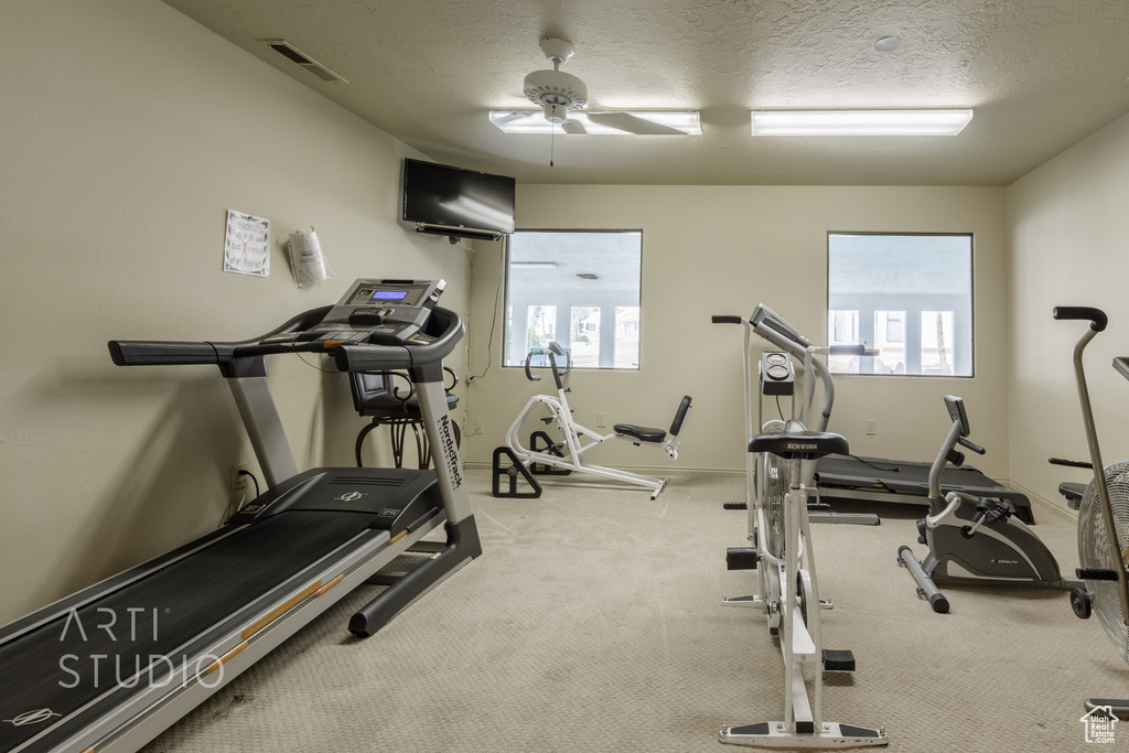 Exercise room with visible vents, ceiling fan, carpet flooring, and a textured ceiling