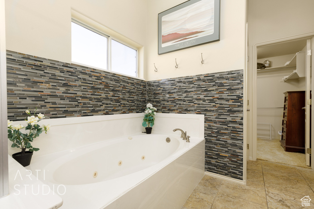 Bathroom featuring a whirlpool tub and tile walls