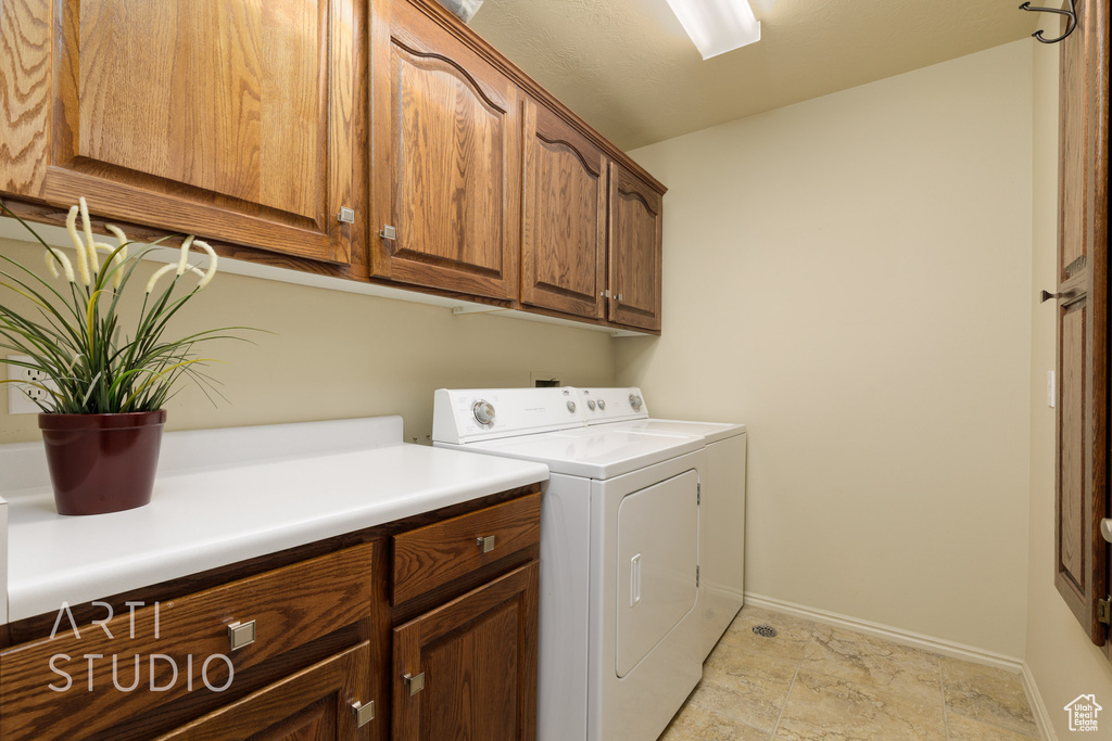 Laundry area featuring baseboards, cabinet space, and washer and clothes dryer