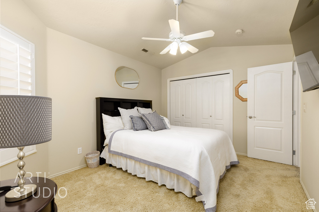 Bedroom featuring visible vents, a closet, light colored carpet, and vaulted ceiling
