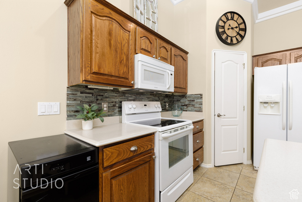 Kitchen with backsplash, light countertops, and white appliances