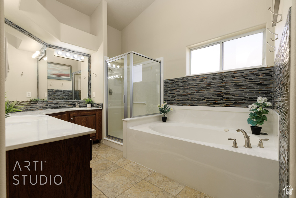 Bathroom with tasteful backsplash, vanity, a stall shower, and a garden tub