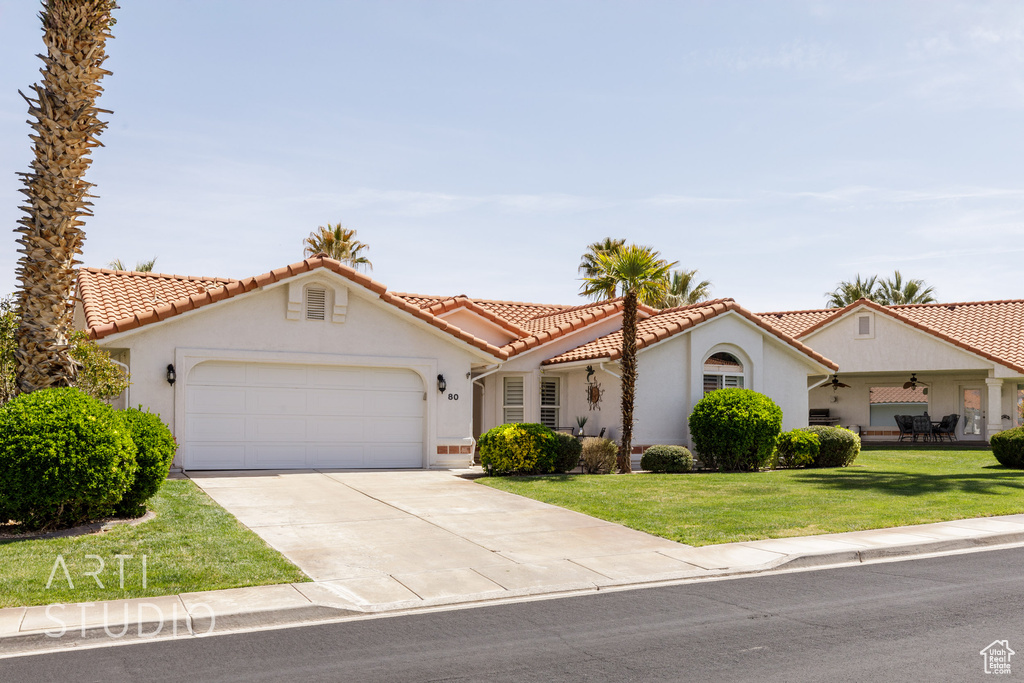 Mediterranean / spanish house featuring concrete driveway, stucco siding, an attached garage, a front yard, and a tile roof