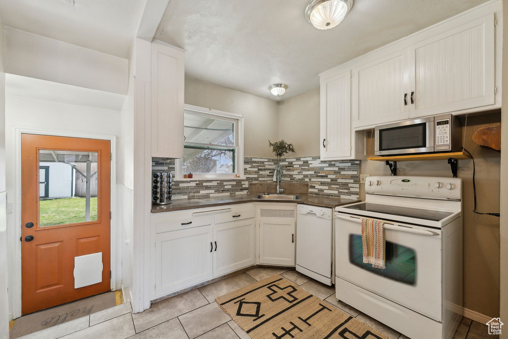 Kitchen with plenty of natural light, white appliances, a sink, and decorative backsplash