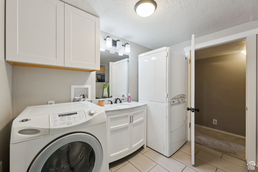Laundry room featuring washer / dryer, a textured ceiling, a sink, and cabinet space