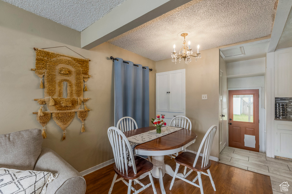 Dining space featuring light wood finished floors, a textured ceiling, baseboards, and a chandelier