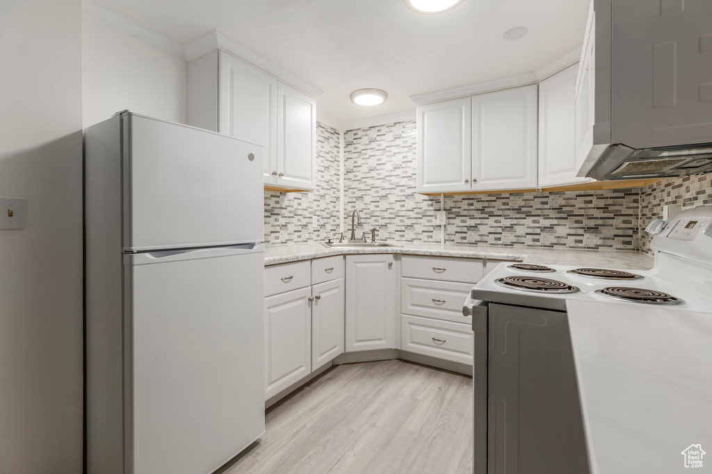 Kitchen with white appliances, a sink, white cabinetry, and decorative backsplash
