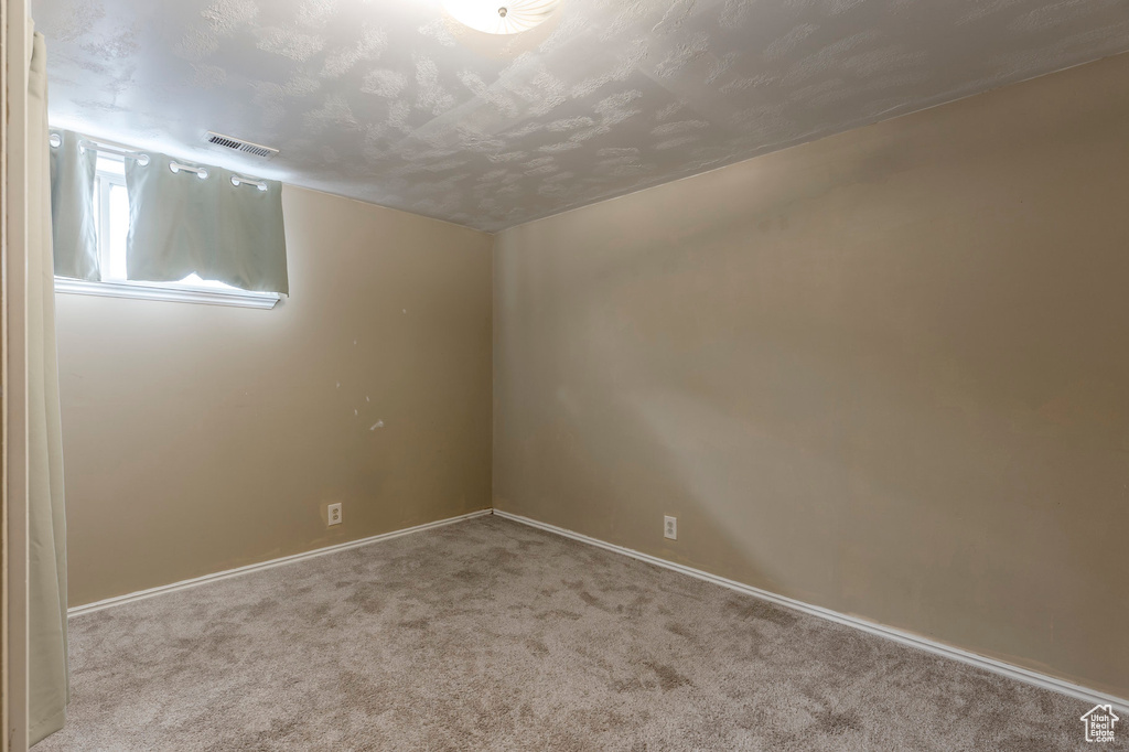 Carpeted spare room featuring baseboards