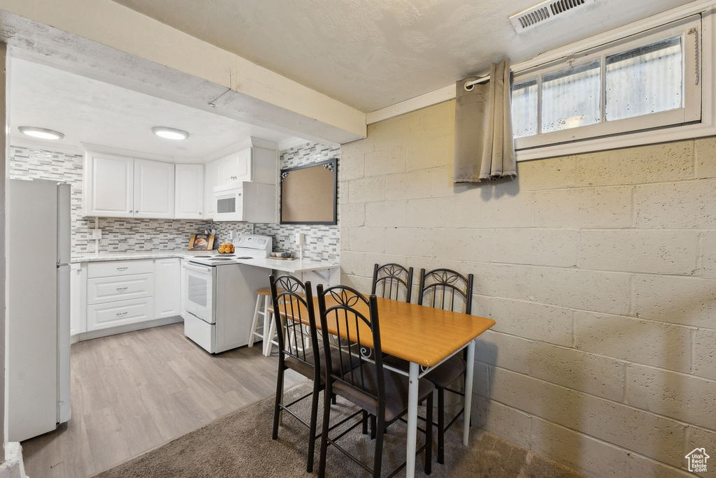 Kitchen with visible vents, white cabinets, light countertops, white appliances, and light wood-style flooring