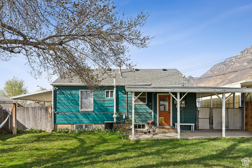Rear view of house with a yard, a shingled roof, fence, and a patio area