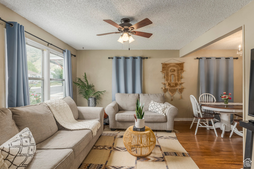 Living area featuring a textured ceiling, wood finished floors, a ceiling fan, and baseboards