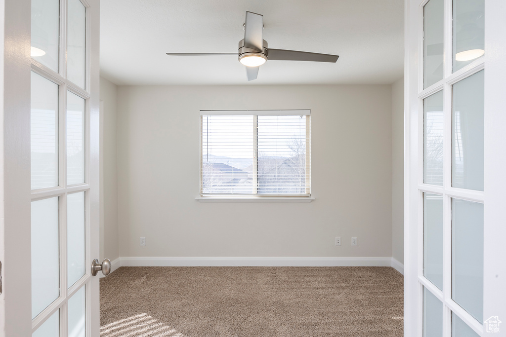 Carpeted spare room with ceiling fan and baseboards