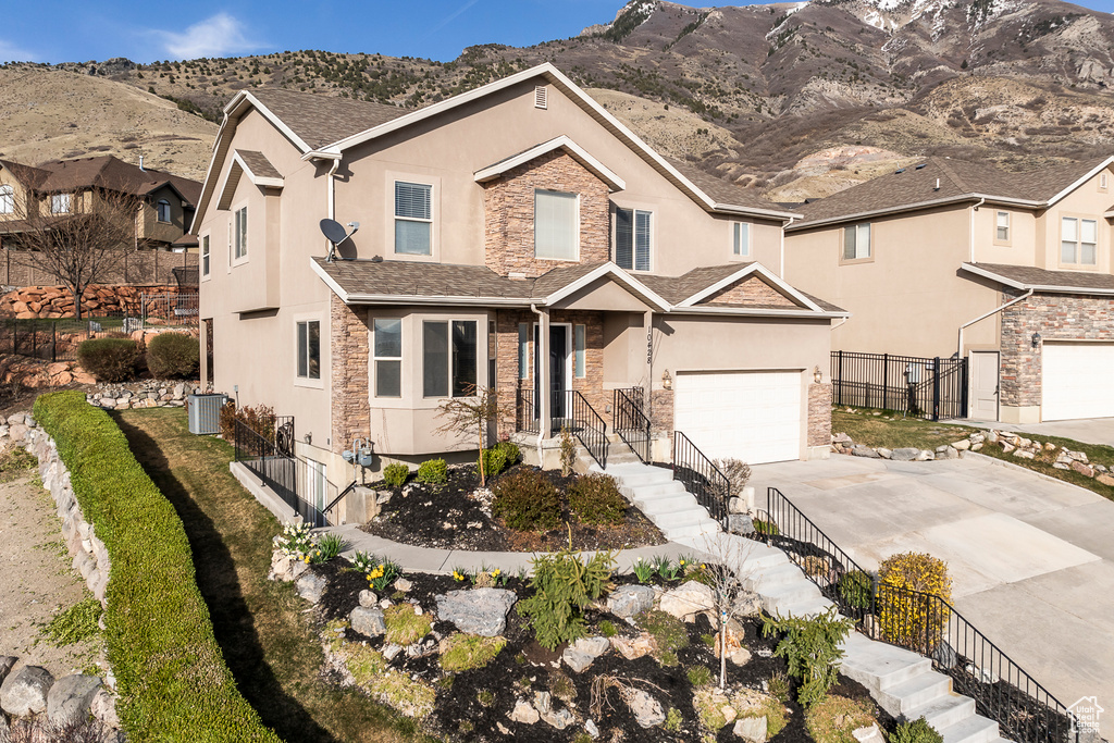 Traditional-style home featuring fence, concrete driveway, stucco siding, and stone siding