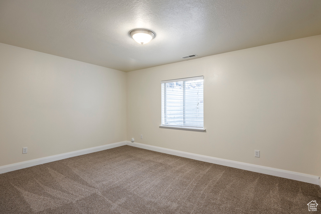 Empty room featuring visible vents, baseboards, and carpet