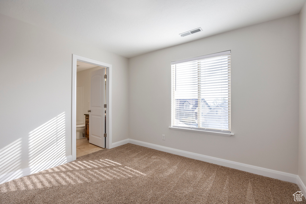 Empty room with visible vents, baseboards, and light colored carpet