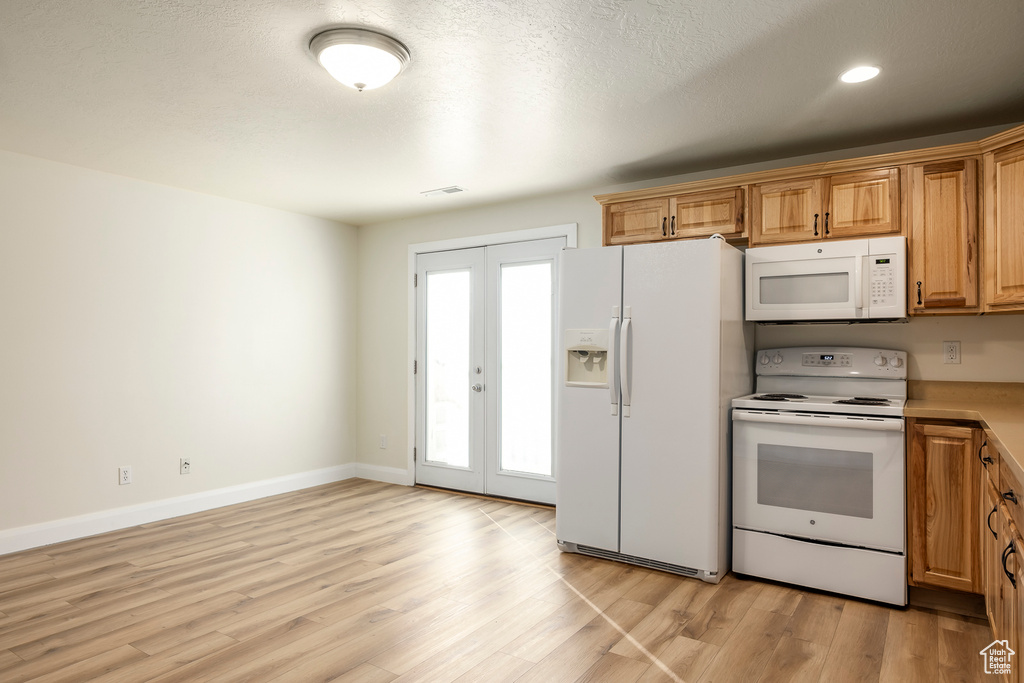 Kitchen featuring white appliances, light wood-style flooring, visible vents, french doors, and baseboards