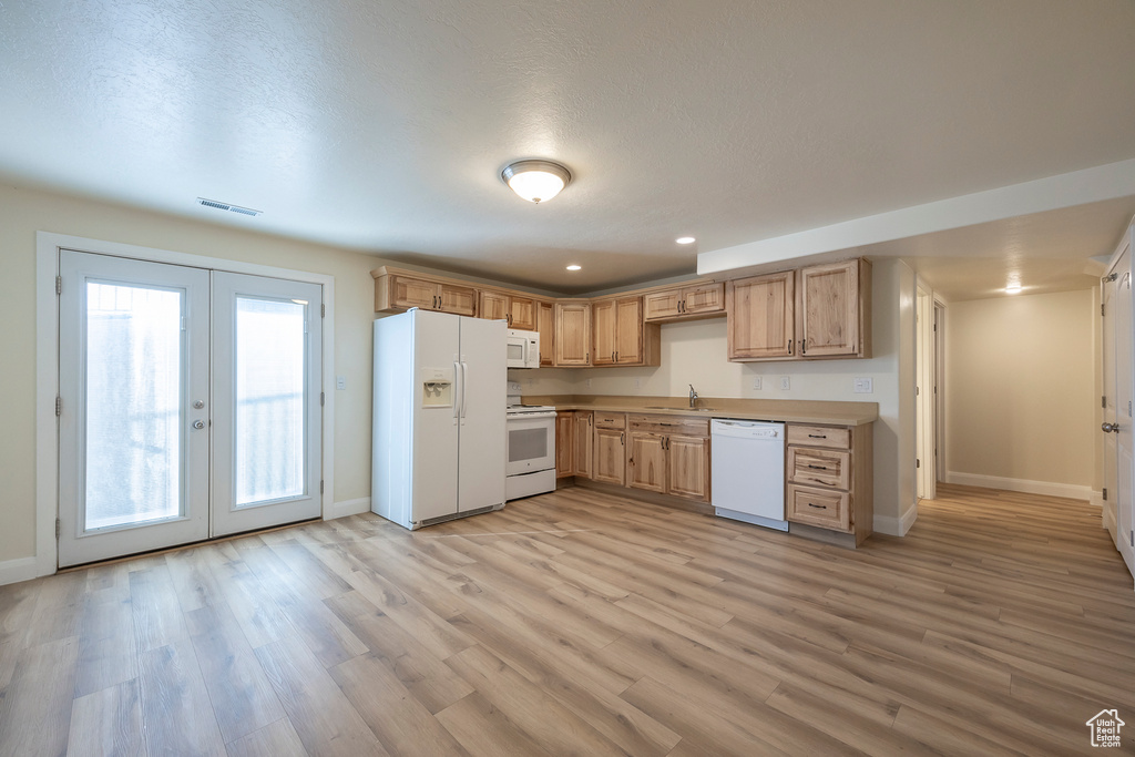 Kitchen with baseboards, light wood-type flooring, white appliances, french doors, and visible vents